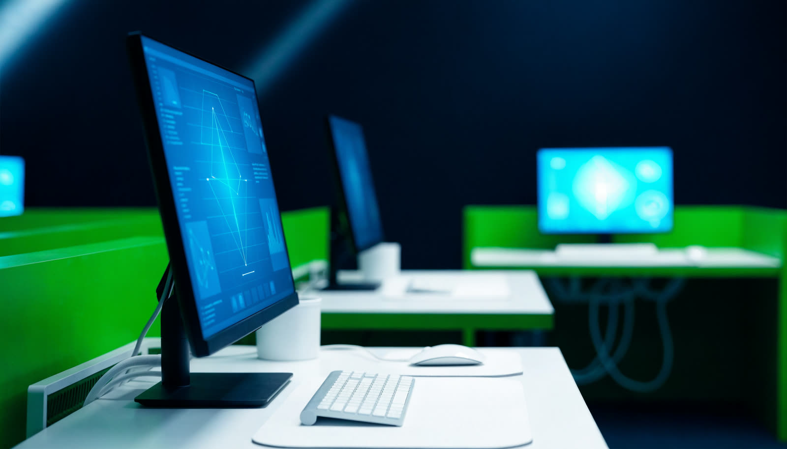 Mavi panolu monitörlerin olduğu düzenli ofis BT ortamı